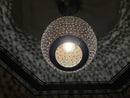 Handcrafted Moroccan brass pendant light illuminating a cozy dining area with its warm glow.
